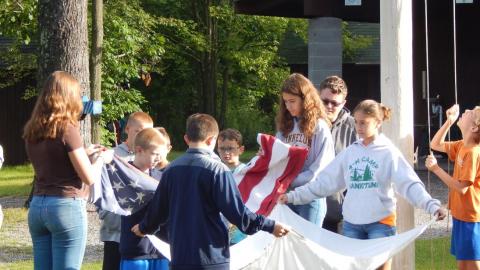 Youth work together to fold the american and 4-h flags.
