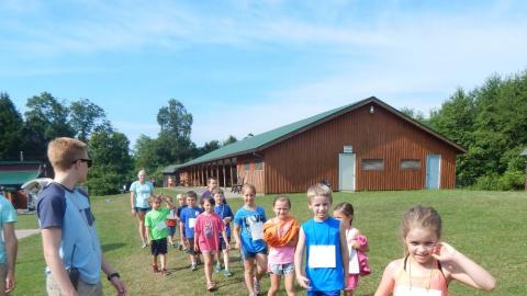 Line of day campers walking toward the camera with counselor in front and back.
