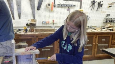 Youth using hand file on bird house.
