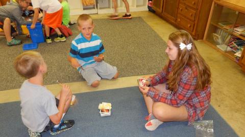 Two youth with counselor playing Uno.