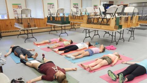Youth in corpse pose on the floor on yoga mats.