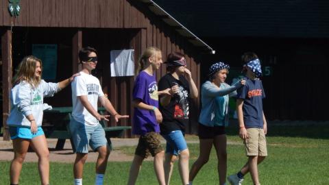 Youth lead a blindfolded partner in pairs during a trust walk.