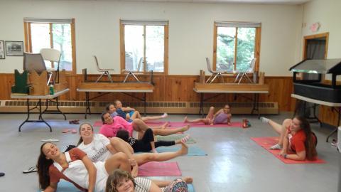 Youth laying on yoga mats with foot raised looking at the camera and smiling.