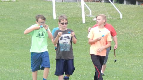 Five youth walk across the field eating popsicles.