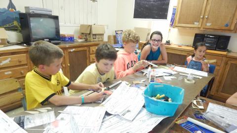 Campers seated around a table building model rockets.