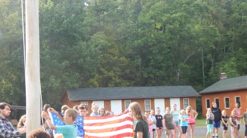 Youth work together to raise the American flag.