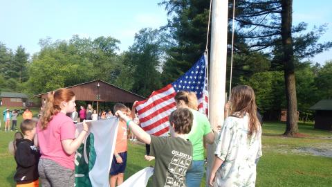 Campers work together to raise the American and 4-H flags.