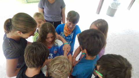 group of campers holding hands in human knot activity.