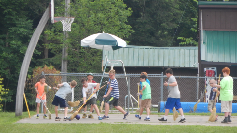 group of youth playing broom hockey on the basketball court.