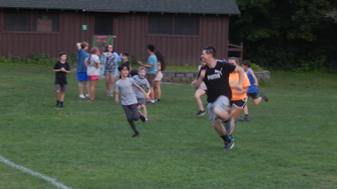 Counselor running from a group of campers who are chasing them.