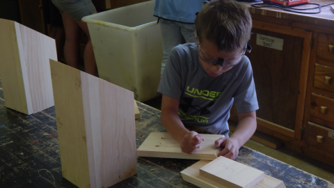 youth wearing goggles while sanding their wood project.
