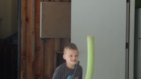 Camper "jousts" riding a broom and carrying a pool noodle.