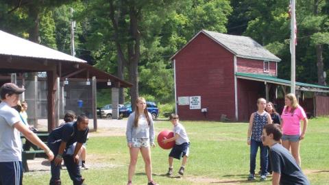 Youth play a game with a giant red ball. 