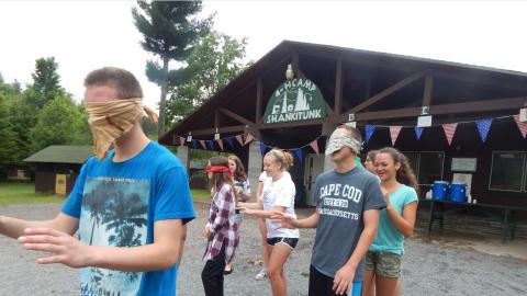 Campers lead a blindfolded partner in pairs during a trust walk.