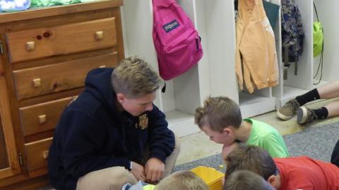 Youth and counselor playing with legos on carpet.