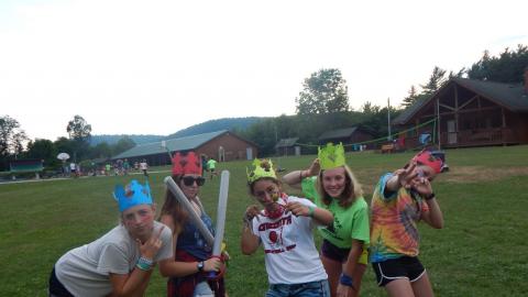 Group of campers posing together with paper crowns and pretend swords.