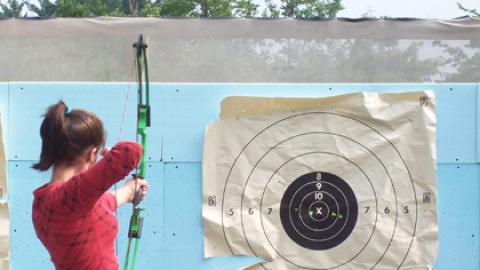 Youth takes aim at a paper target in Archery class.
