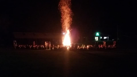 Campers and staff around a large bonfire.