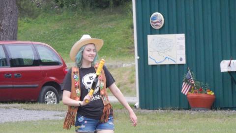 Counselor dressed as cowgirl carrying water gun.