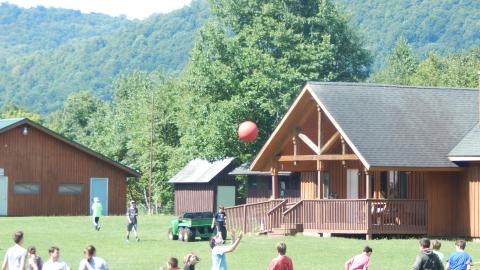 Counselor prepares to catch a ball falling from overhead as the campers run away from them.