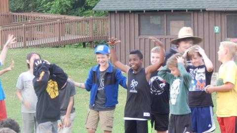 Cabin group in a line holding their heads and laughing.