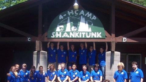 Camp staff pose for a photo in front of the 4-H Camp Shankitunk sign. 