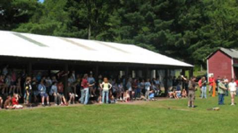 campers and staff gathered together in the recreation pavilion  as rockets are launched in the field.