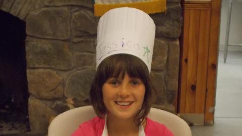 camper holding culinary creation wearing chef's hat