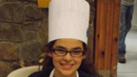 camper holding culinary creation wearing chef's hat