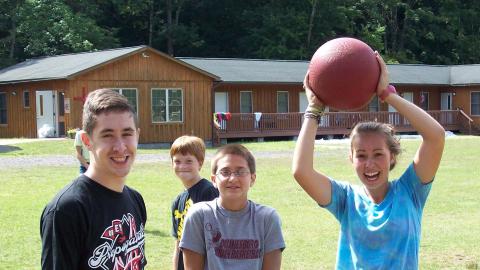 campers smiling with counselor holding a ball 