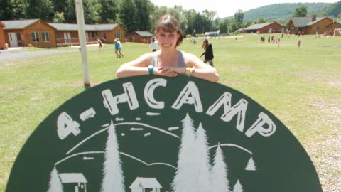 Staff standing in front of their handpainted 4-H Camp Shankitunk sign