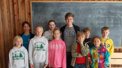 campers standing with counselor in front of chalkboard 