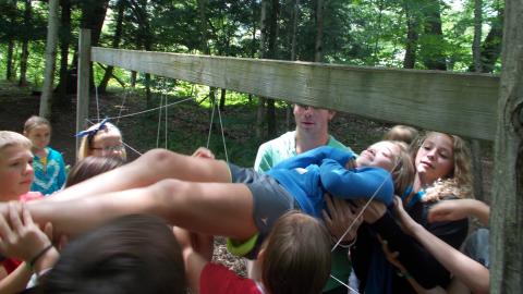 campers putting youth through ropes obstacle course 