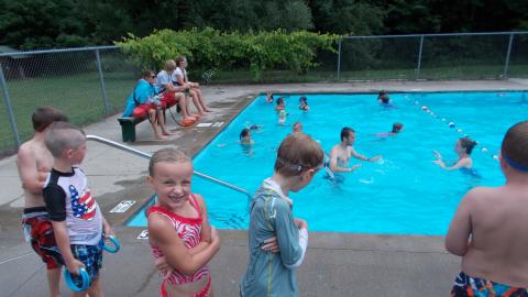 campers standing by swimming pool with campers swimming in the pool in the background