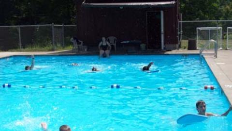 Campers swimming with kick boards in the pool. 