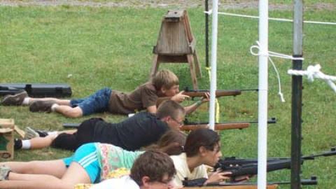 Campers firing air rifles laying down in prone position.