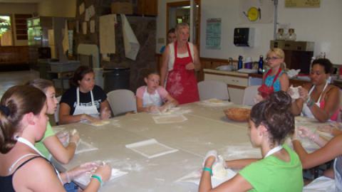 Youth listen to an instructor teach a cooking class. 