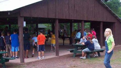 youth playing inside and outside the recreation pavilion during recreation time with counselors nearby supervising.