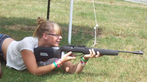 Teen laying in prone position taking aim with air rifle.