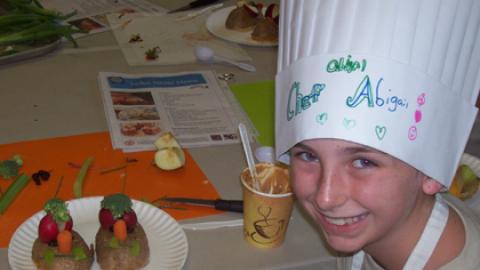 Smiling chef Abigail with a veggie baked potato creation.
