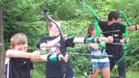youth on the firing line draw their bow and prepare to fire their arrows.