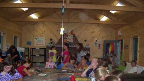 many campers scattered around the craft hall working on different projects.