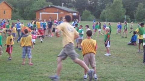 Camp-wide game of pirate ball. Youth and staff running about between four marked sections of the field.