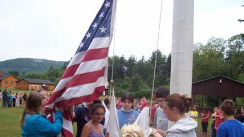 Youth working together to raise the american flag.