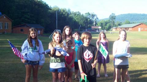 Group of youth carrying small american and 4-H flags toward camera.