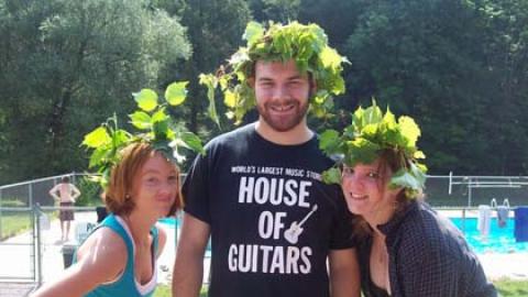 three smiling staff pose together wearing crowns made of leafy vines.