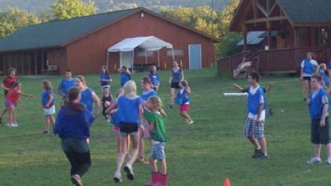 large group of campers and counselors wearing blue, red, and green pinnies playing pirate ball.