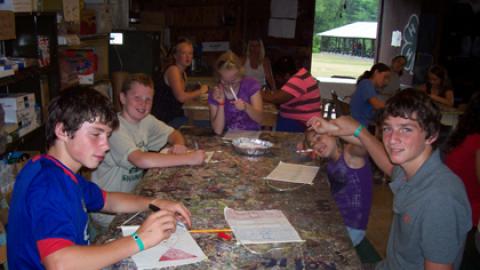 Group of youth around tables doing crafts of their choice during a recreation period.
