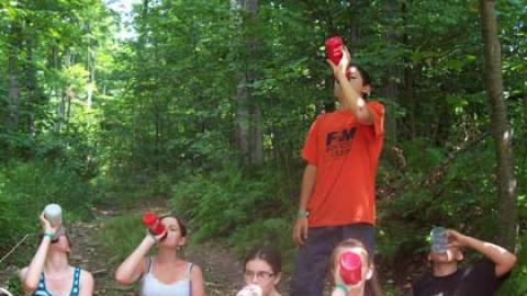 Campers drinking water in the woods. 