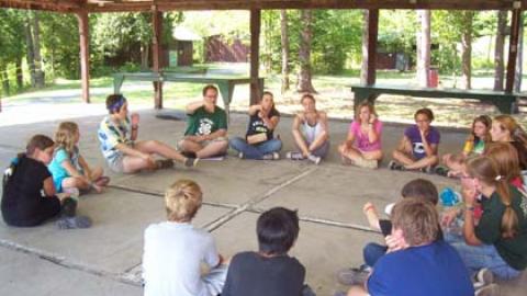 Youth sit in a circle while counselors introduce them to the sign language alphabet.
